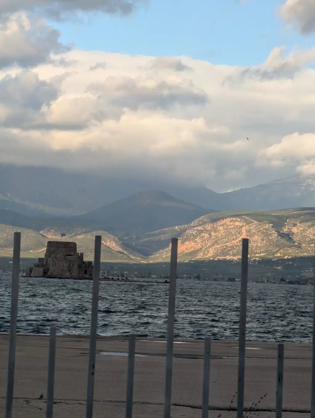 Die Festung Bourtzi in der Bucht von Nafplio, im Vordergrund ein Zaun am Ufer