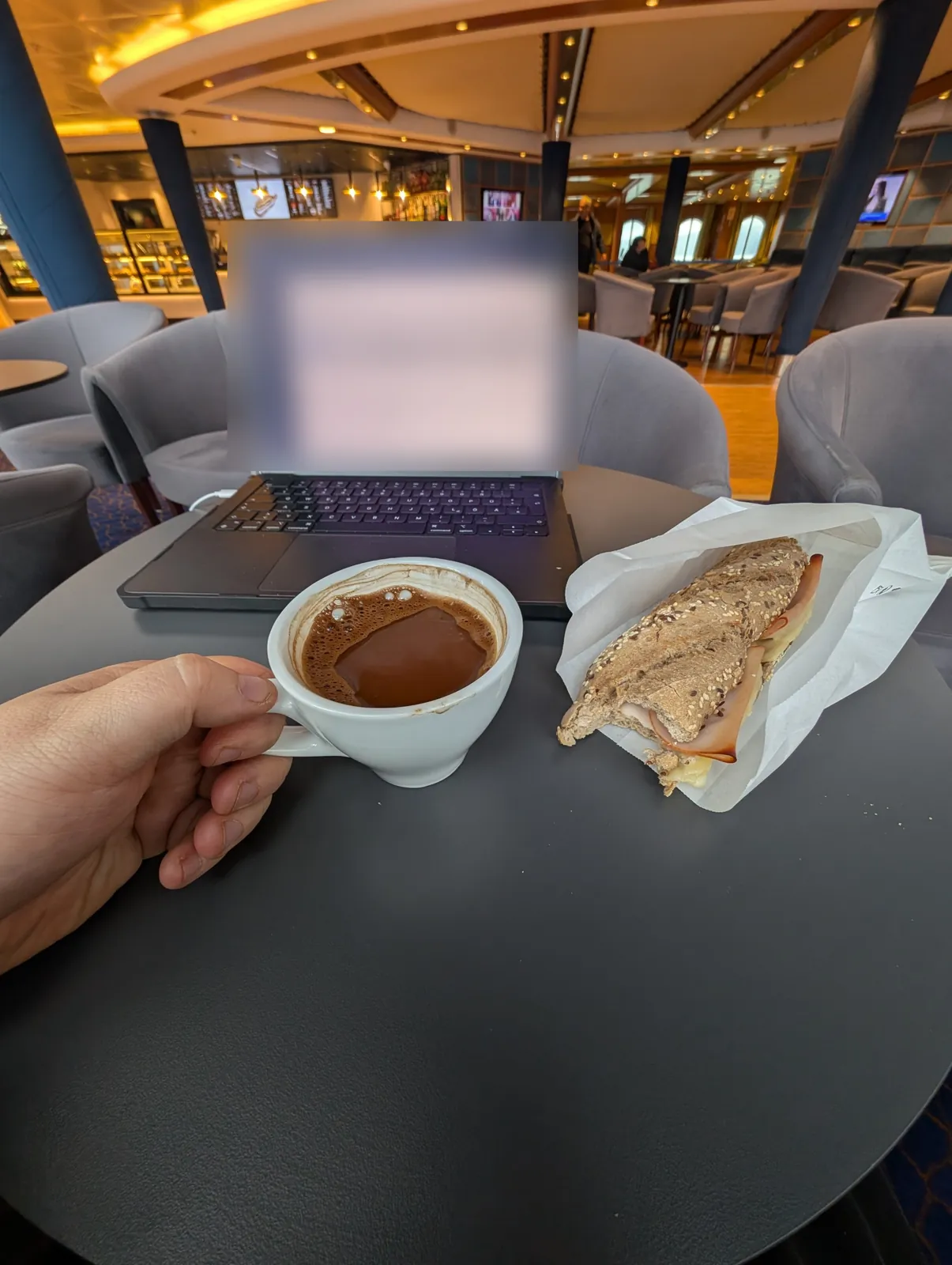 Laptop, Kaffee und Sandwich auf einem Tisch in der Lounge der Superfast III
